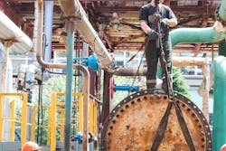 Workers mount a shell-and-tube heat exchanger at an oil refining petrochemical chemical industrial plant during a scheduled shutdown repair. Workers mount a shell-and-tube heat exchanger at an oil refining petrochemical chemical industrial plant during a scheduled shutdown repair.