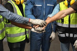 Group of technician engineer or worker in protective uniform with hardhat standing and stacking hands Group of technician engineer or worker in protective uniform with hardhat standing and stacking hands