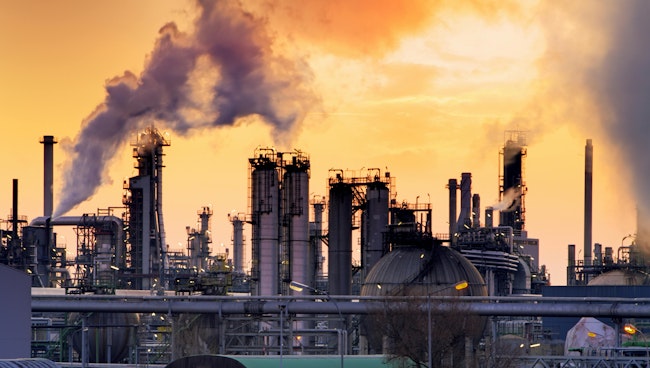 chemical plant with emissions against a yellow sky