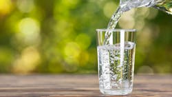 water from jug pouring into glass on wooden table outdoors water from jug pouring into glass on wooden table outdoors