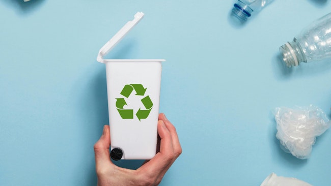 Hand holding a recycling garbage bin with lots of waste packaging