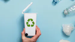 Hand holding a recycling garbage bin with lots of waste packaging