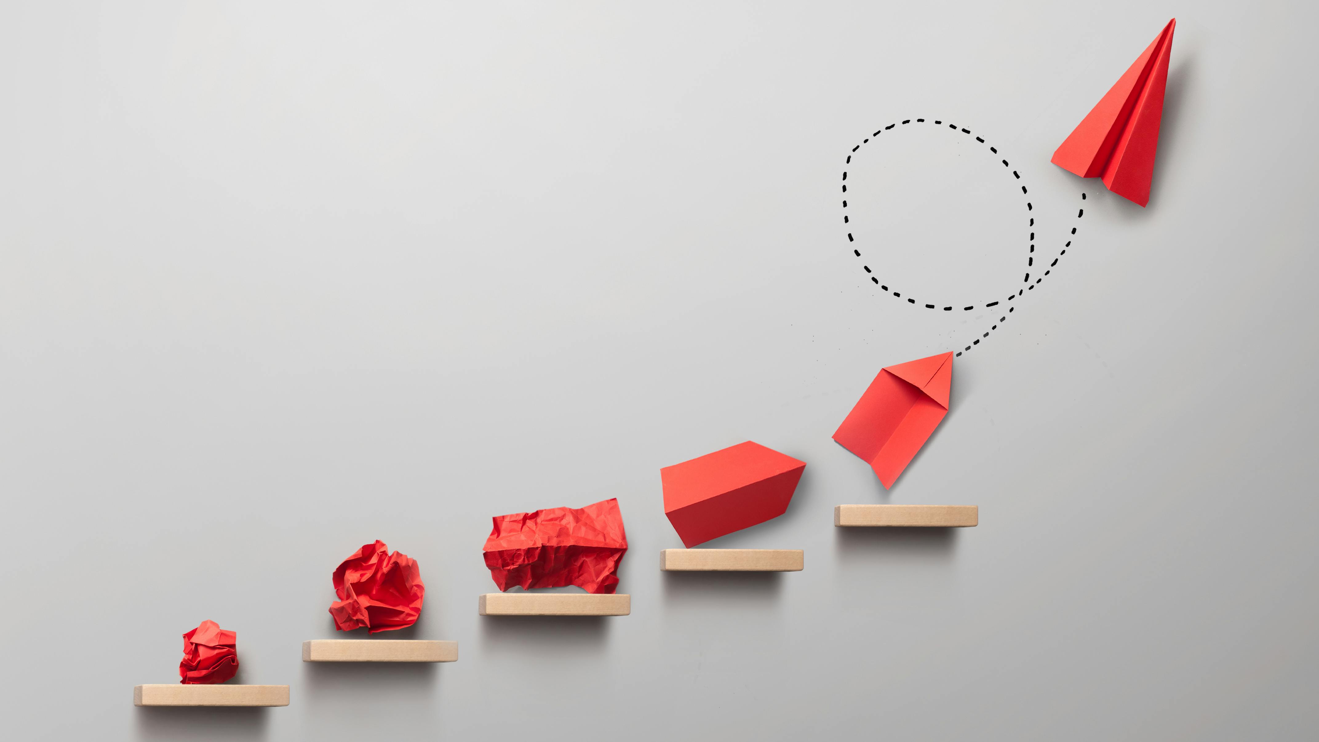 Wooden steps with different stages of making a paper airplane, creating something from nothing success concept