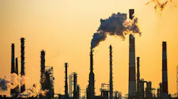Working oil refinery against yellow dusk sky