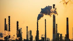 Working oil refinery against yellow dusk sky Working oil refinery against yellow dusk sky