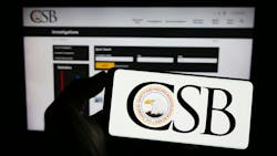 Person holding mobile phone with logo of federal agency U.S. CSB on screen in front of web page Person holding mobile phone with logo of federal agency U.S. CSB on screen in front of web page