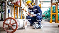 Hardworking industrial technician inspecting high pressure valve inside refinery plant. Hardworking industrial technician inspecting high pressure valve inside refinery plant.
