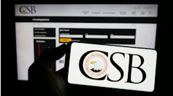 Person holding mobile phone with logo of federal agency U.S. CSB on screen in front of web page. F Person holding mobile phone with logo of federal agency U.S. CSB on screen in front of web page. F