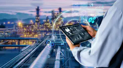 Hands holding tablet with Chemical plant blurred in background