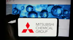 Person holding cellphone with logo of company Mitsubishi Chemical Group Corporation on screen in front of business webpage. Focus on phone display.