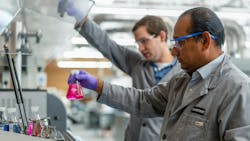 researchers handle Erlenmeyer flask with bring pink fluid researchers handle Erlenmeyer flask with bring pink fluid