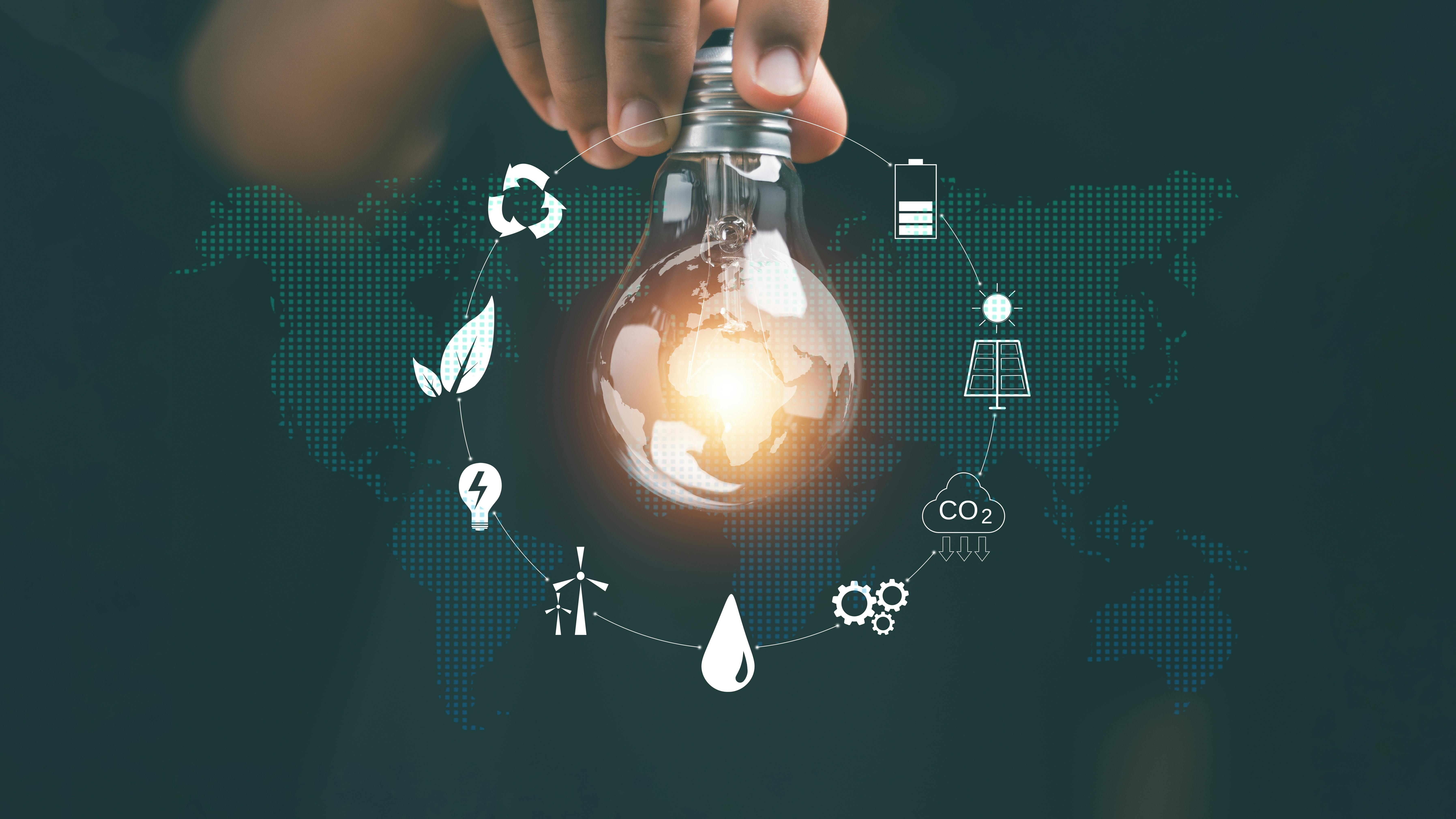 Hand holding light bulb with icons for green energy sources and renewables
