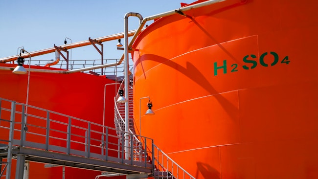 Orange metal storage tanks with sulfuric acid and its formula on tank