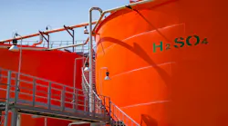 Orange metal storage tanks with sulfuric acid and its formula on tank