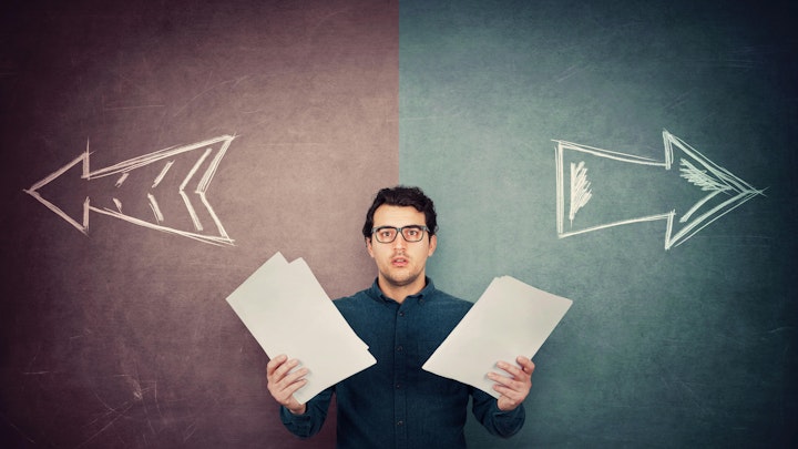 Perplexed businessman has to choose as holds different paper documents in both hands.