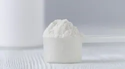 a scoop with white powder closeup and a jar on gray background
