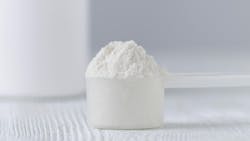 a scoop with white powder closeup and a jar on gray background a scoop with white powder closeup and a jar on gray background