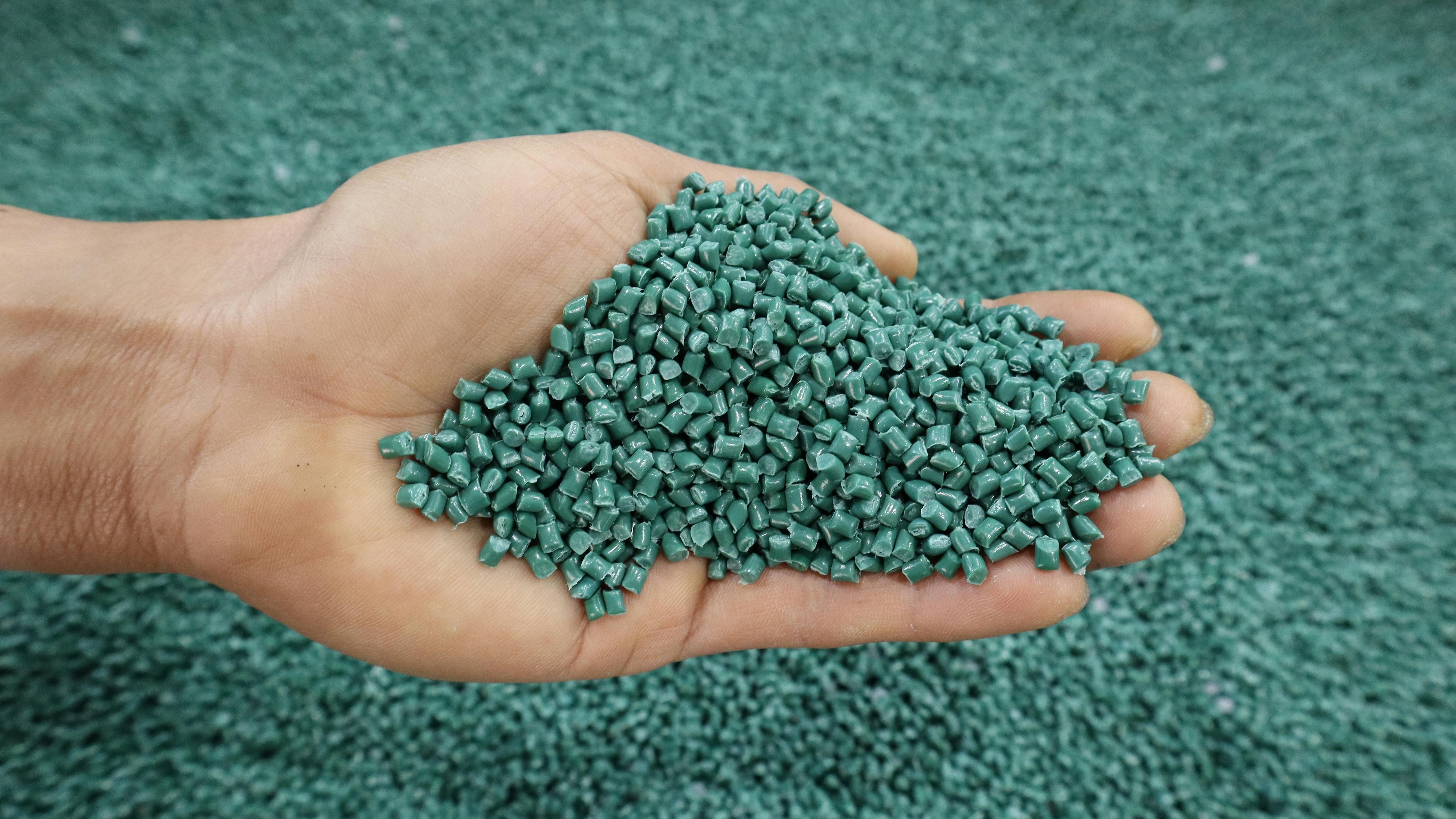 Plastic pellets for production, plastic polymer dye granules color green.