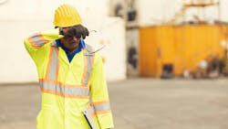 African American worker in safety apparely and hard hat, wiping brow to combat sweat and heat African American worker in safety apparely and hard hat, wiping brow to combat sweat and heat