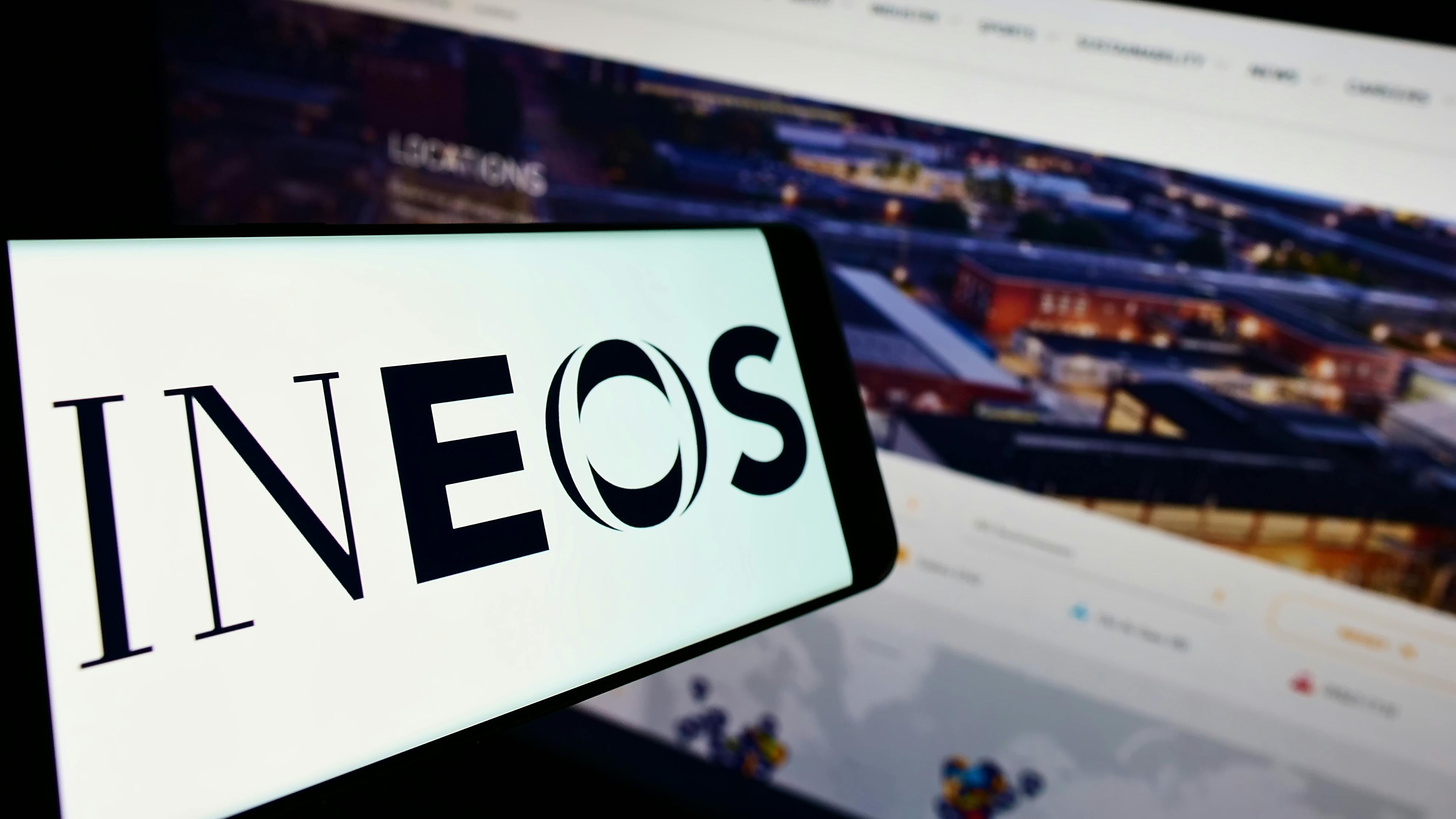 INEOS logo on smart phone display with computer monitor of INEOS website in background
