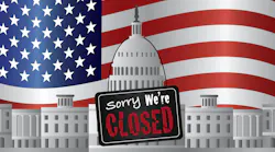 US government building with a Sorry we're closed sign and US flag in background