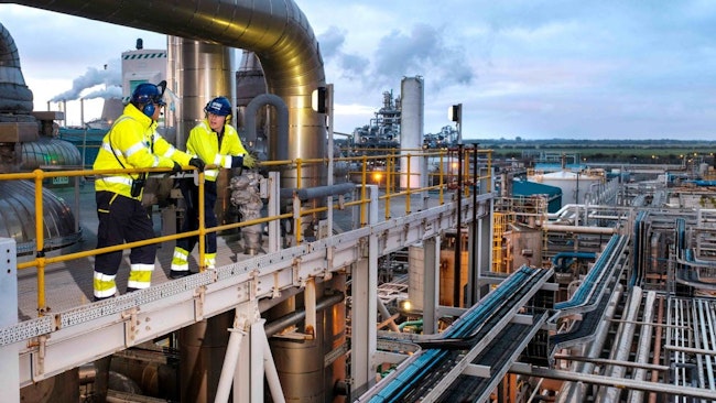 Two workers in safety gear stand on scaffold above Ineos acetyls plant in UK