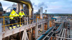 Two workers in safety gear stand on scaffold above Ineos acetyls plant in UK