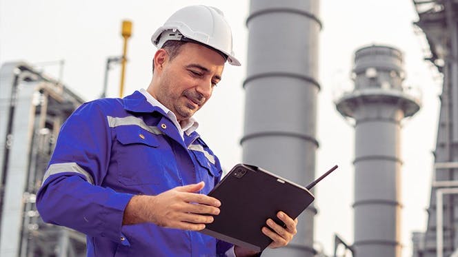 Male industrial worker in hard hat with tablet
