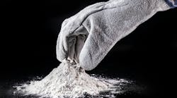 gloved hand reaches into small pile of powder surrounded by black background gloved hand reaches into small pile of powder surrounded by black background