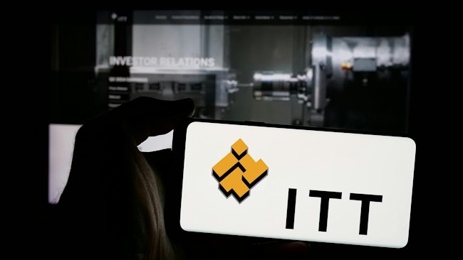 Person holding mobile phone with logo of American industrial manufacturing company ITT Inc. on screen in front of web page. Focus on phone display. Unmodified photo.