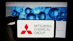 Mitsubishi Chemical Group logo displayed on phone screen with company website on computer screen in background Mitsubishi Chemical Group logo displayed on phone screen with company website on computer screen in background