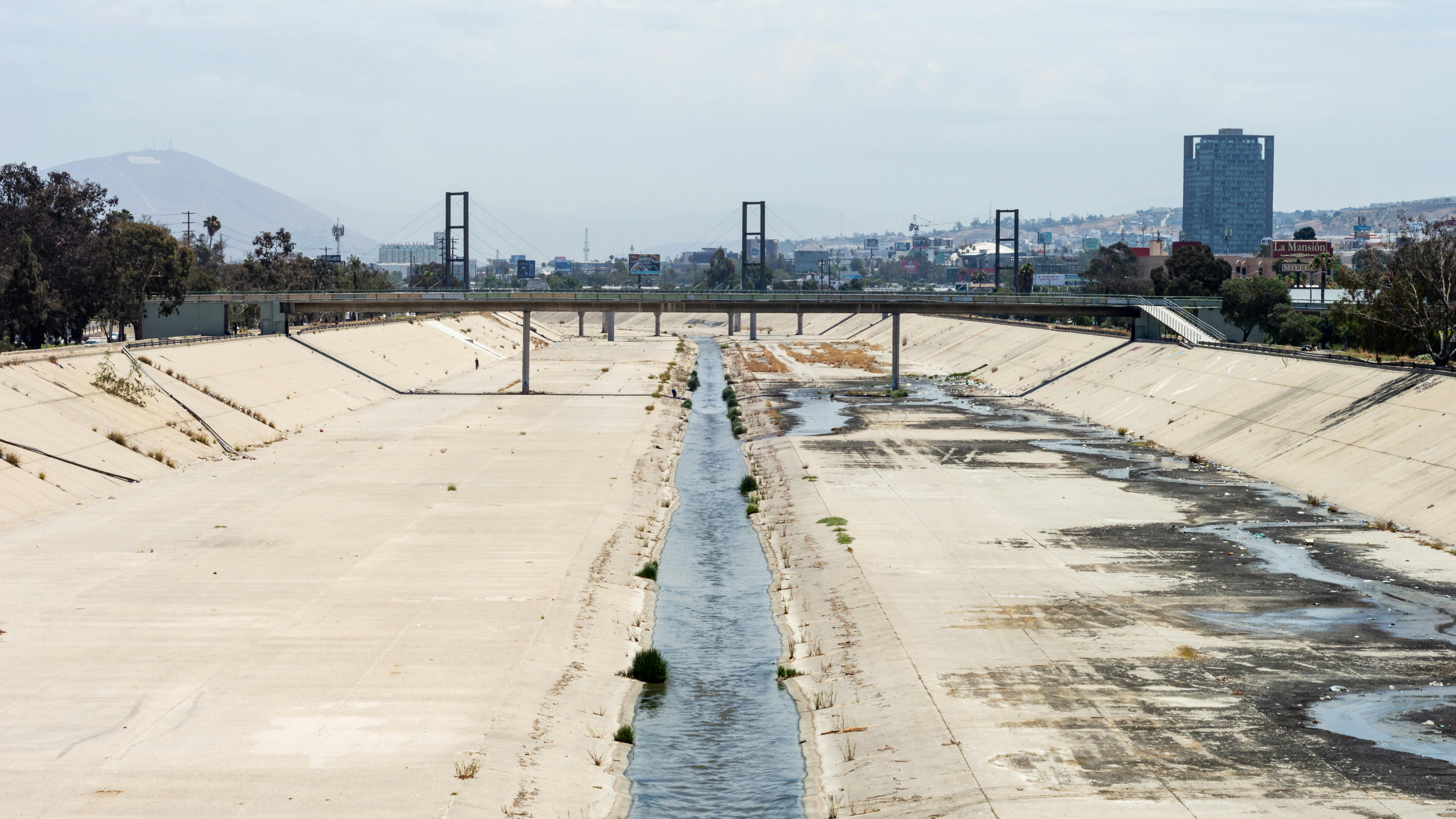 Tijuana river under a bridge with the colored hill (cerro colorado) in the background.