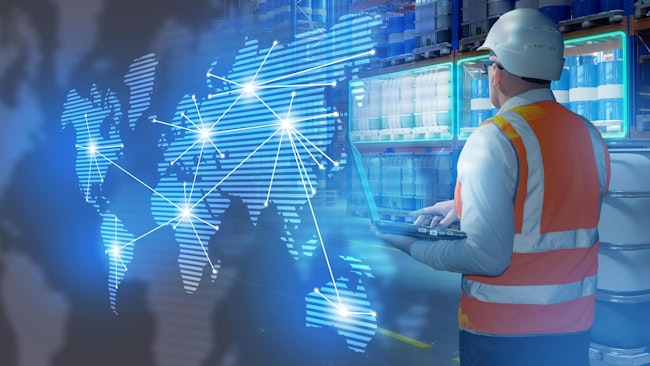 Warehouseman stands in warehouse with barrels. International logistics supply chains. Man logistician holding laptop with his back to camera.