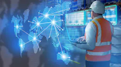 Warehouseman stands in warehouse with barrels. International logistics supply chains. Man logistician holding laptop with his back to camera.