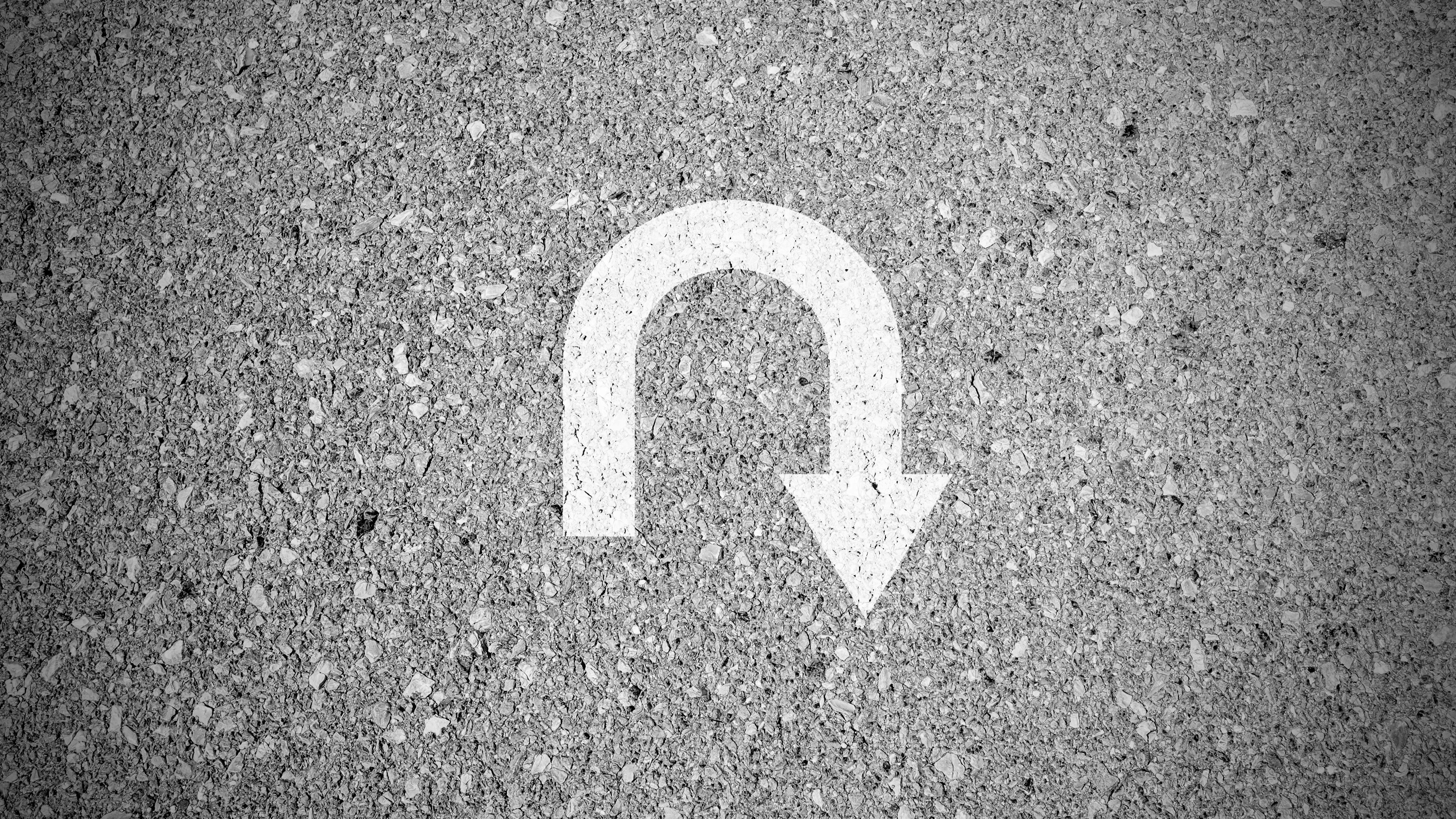 White u turn sign on asphalt concret street as background