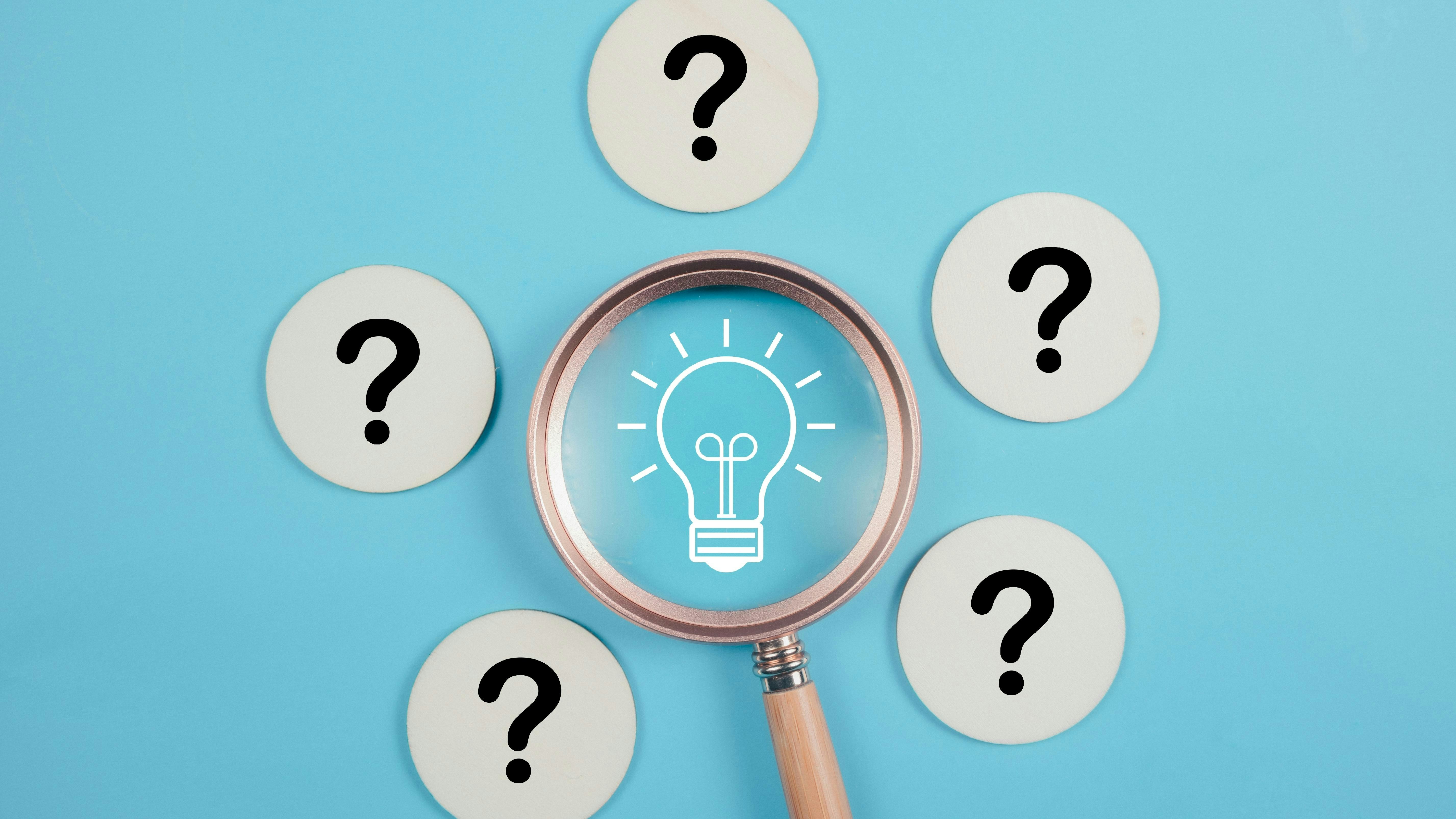 magnifying glass over image of light bulb surrounded by five question marks