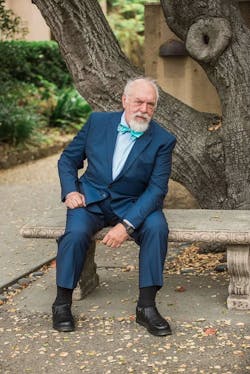 Dave Russell in suit and bow tie sitting on park bench under a tree Dave Russell in suit and bow tie sitting on park bench under a tree