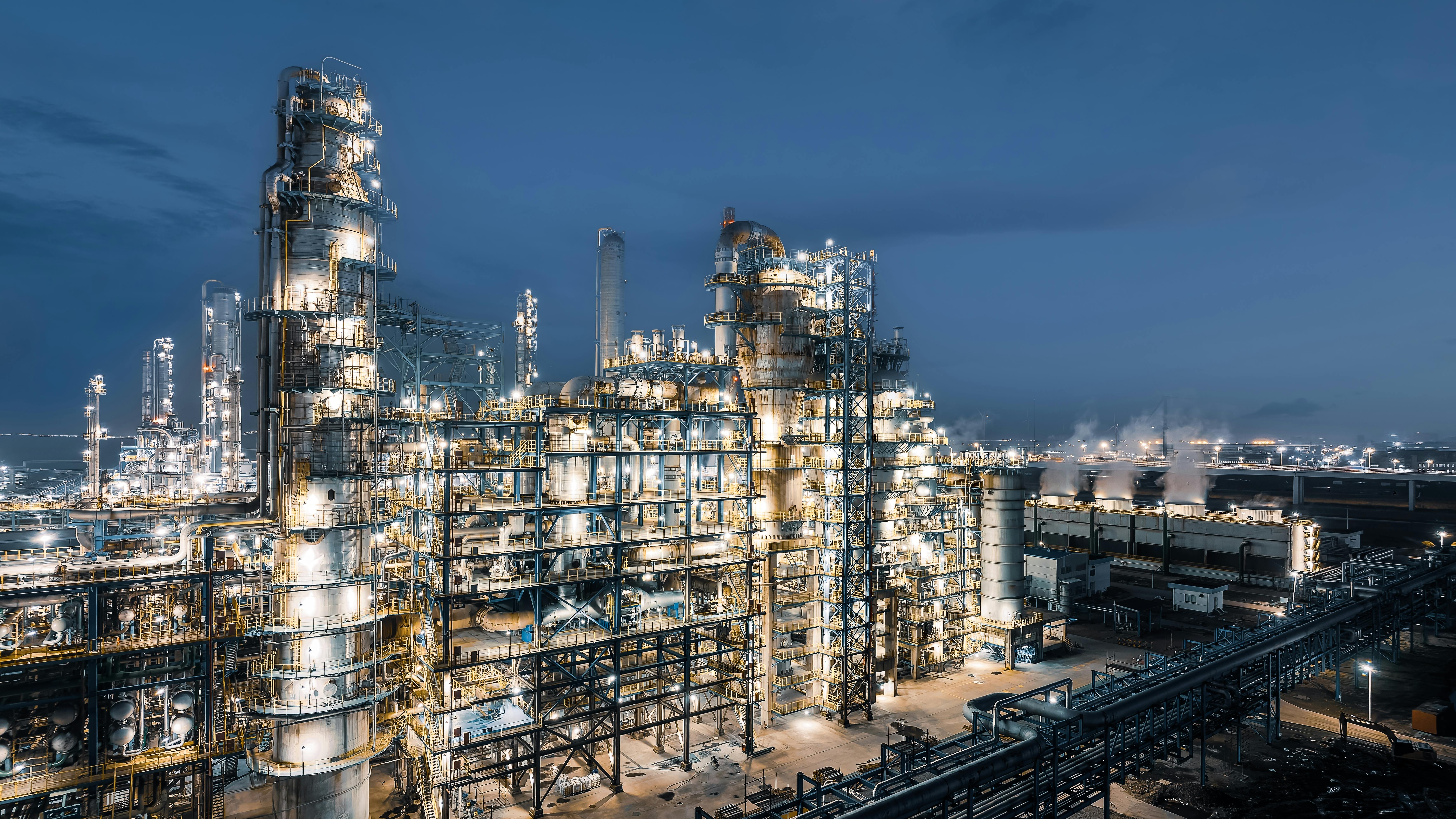 Industrial chemical plant equipment and pipelines at night view.