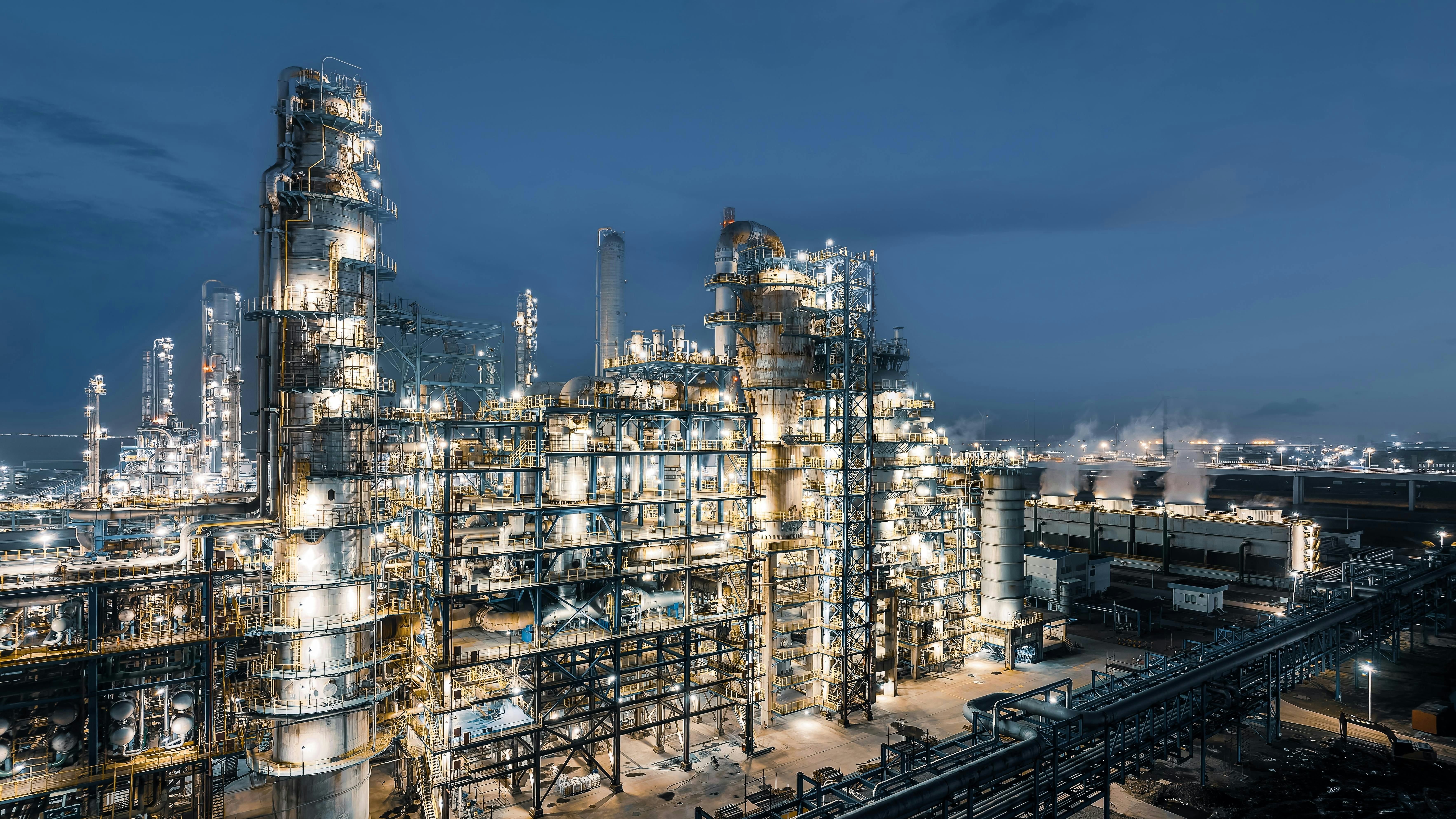 Industrial chemical plant equipment and pipelines at night view.