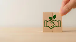 Four wooden blocks stacked together to reveal image of handshake with a green leaf included