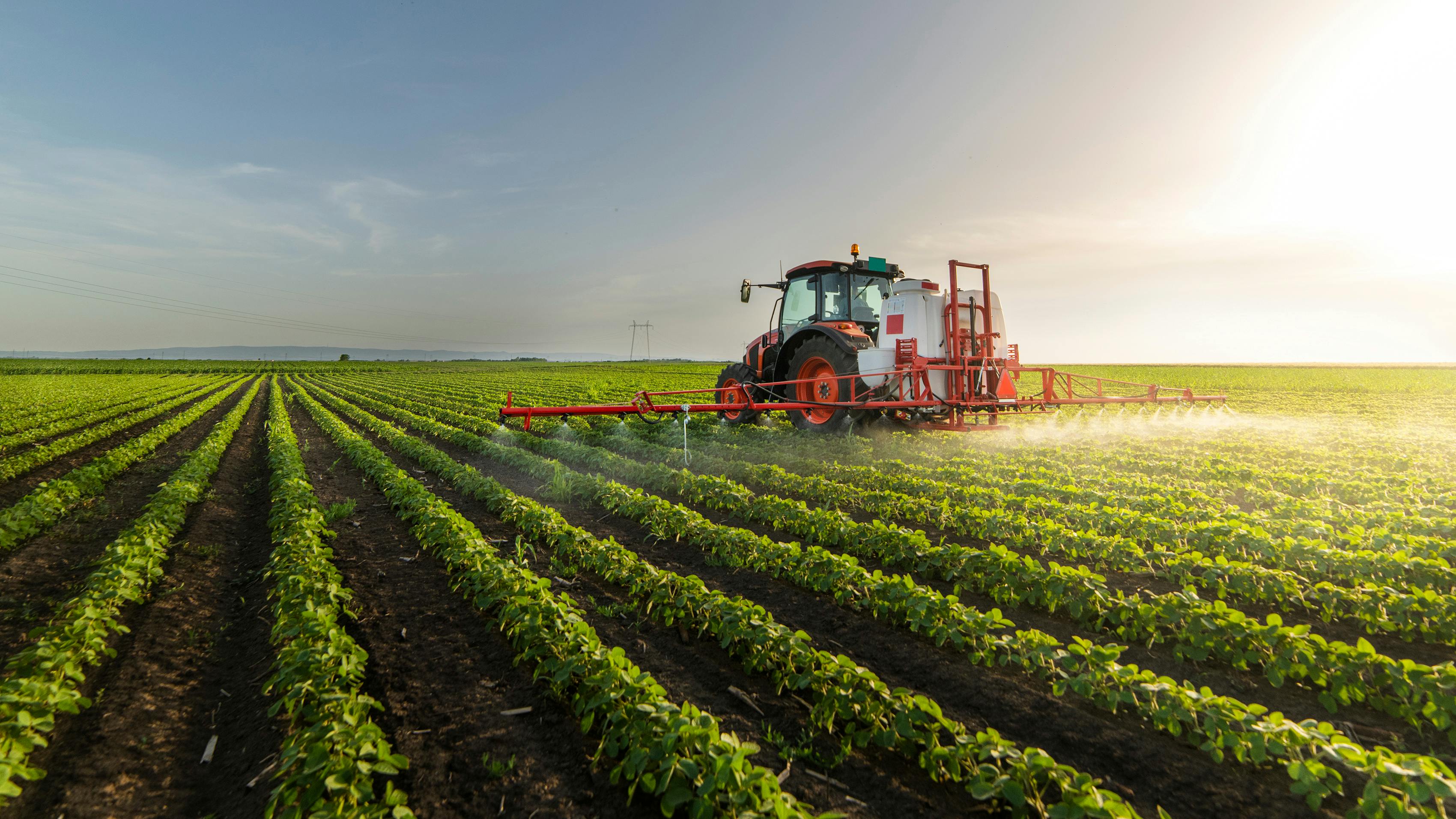 tractor spraying chemicals on soybean field
