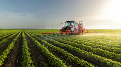 tractor spraying chemicals on soybean field