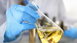 hands in protective gloves hold test tube filled with liquid chemical for testing