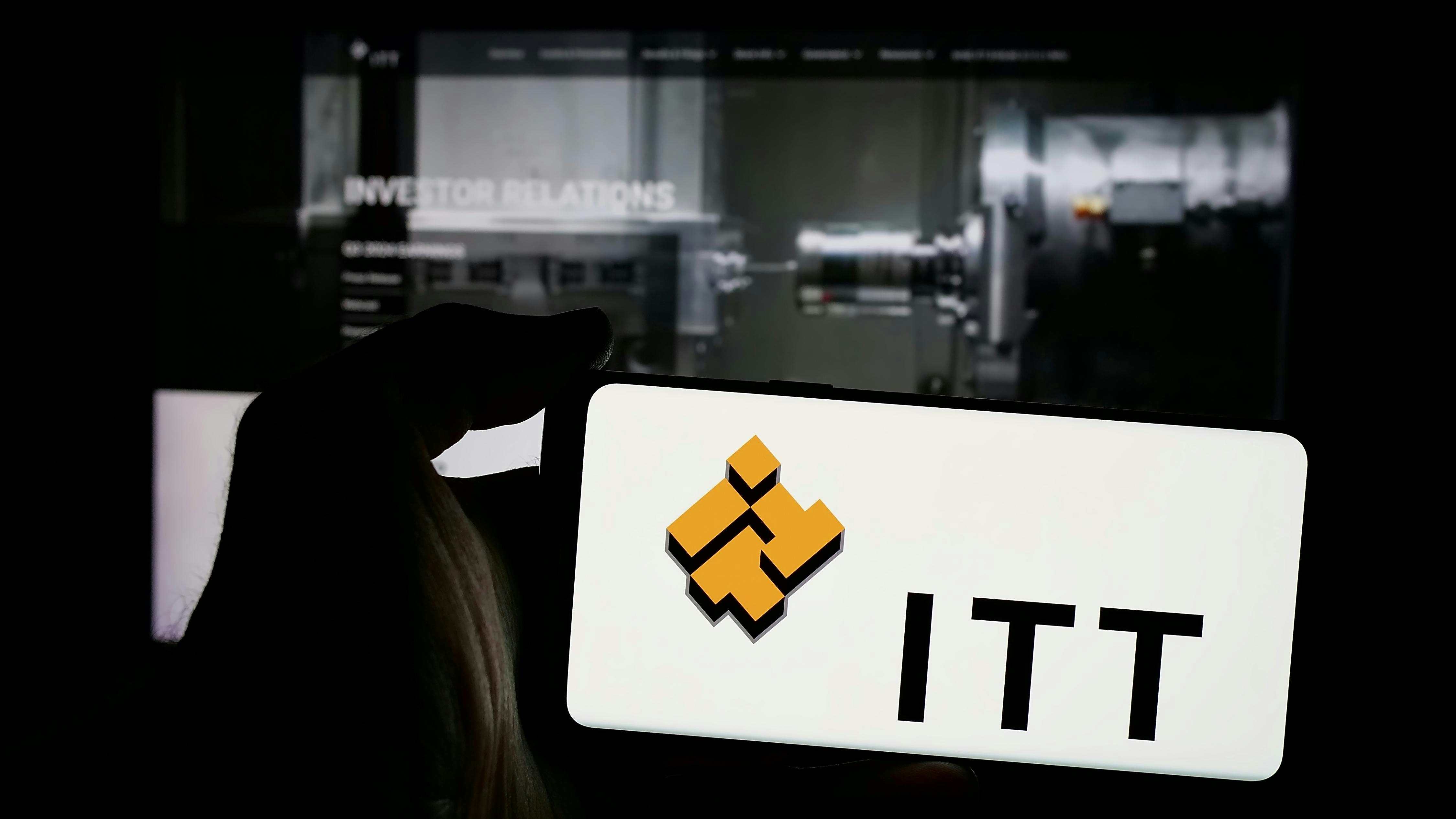 Person holding mobile phone with logo of American industrial manufacturing company ITT Inc. on screen in front of web page. Focus on phone display. Unmodified photo.