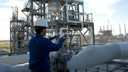 Industrial worker in blue coveralls and white hard hat operating a valve at Shintech Louisiana site Industrial worker in blue coveralls and white hard hat operating a valve at Shintech Louisiana site