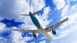 Commercial passenger aircraft photographed from below during flight, showing its white fuselage with blue tail fin and wing accents against a blue sky with white clouds. Commercial passenger aircraft photographed from below during flight, showing its white fuselage with blue tail fin and wing accents against a blue sky with white clouds.