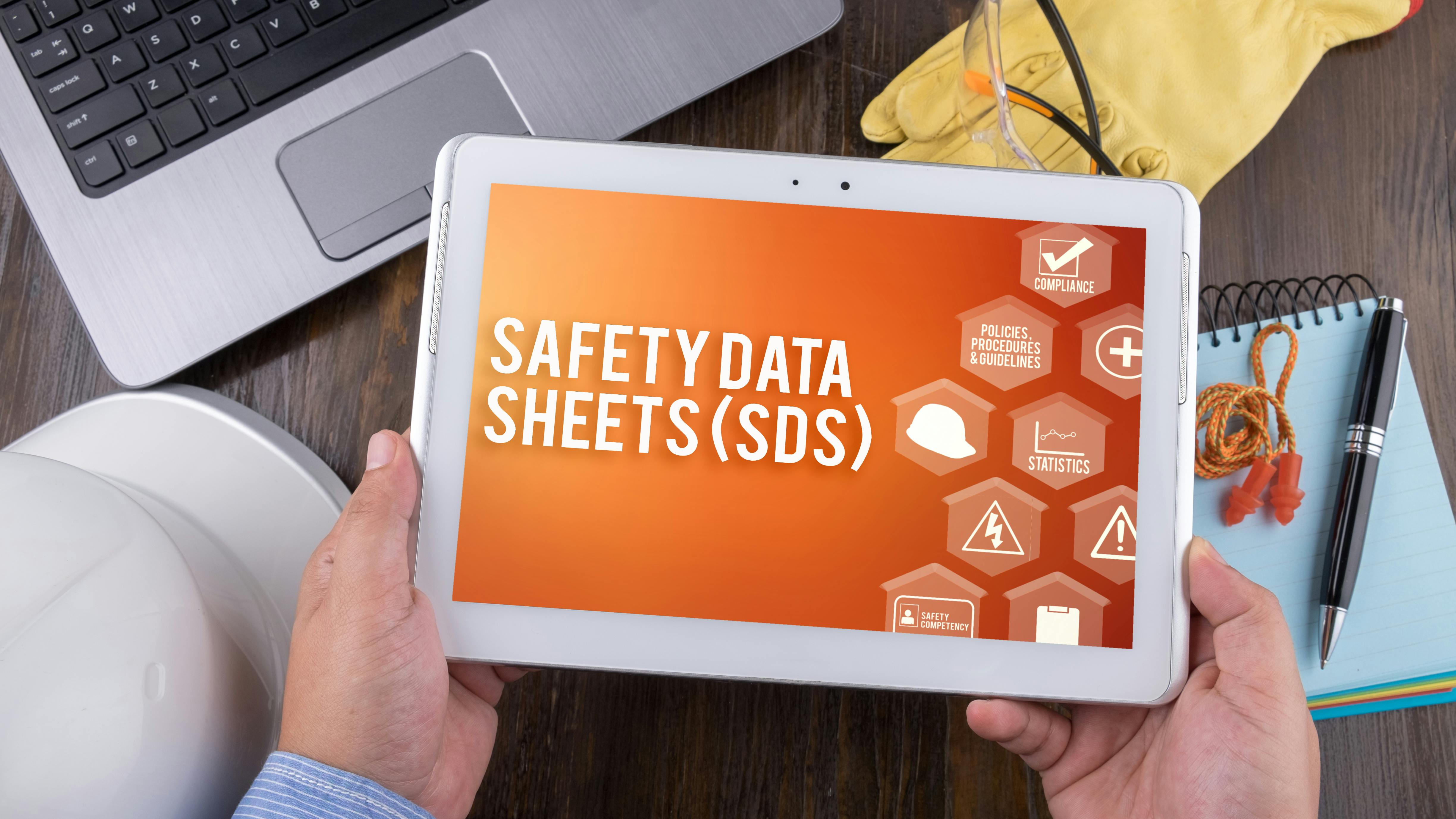 Worker holds tablet with Safety Data Sheets (SDS) displayed on screen