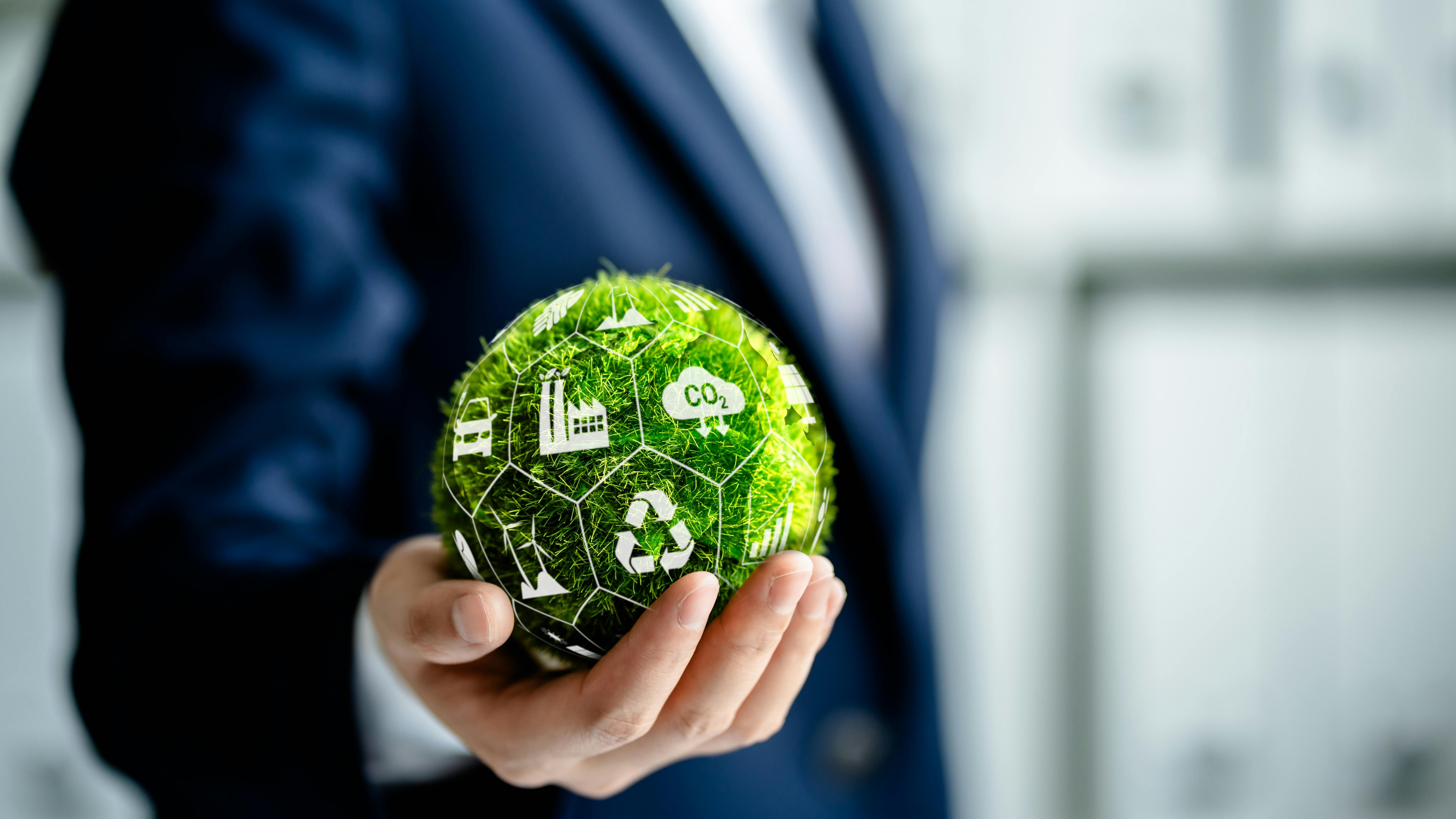 Businessman holding green ball made of grass, surrounded by environment icons.
