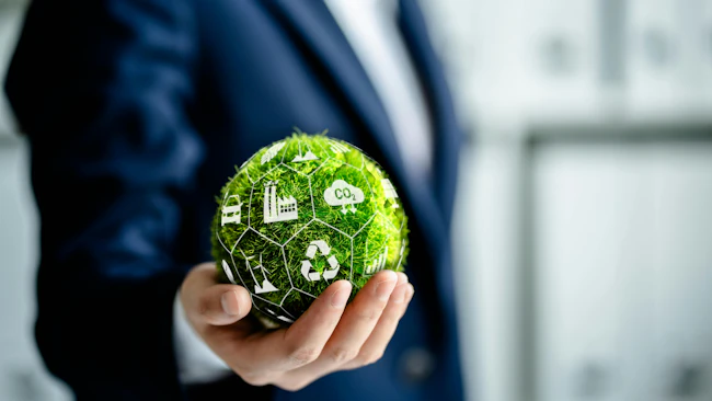 Businessman holding green ball made of grass, surrounded by environment icons.
