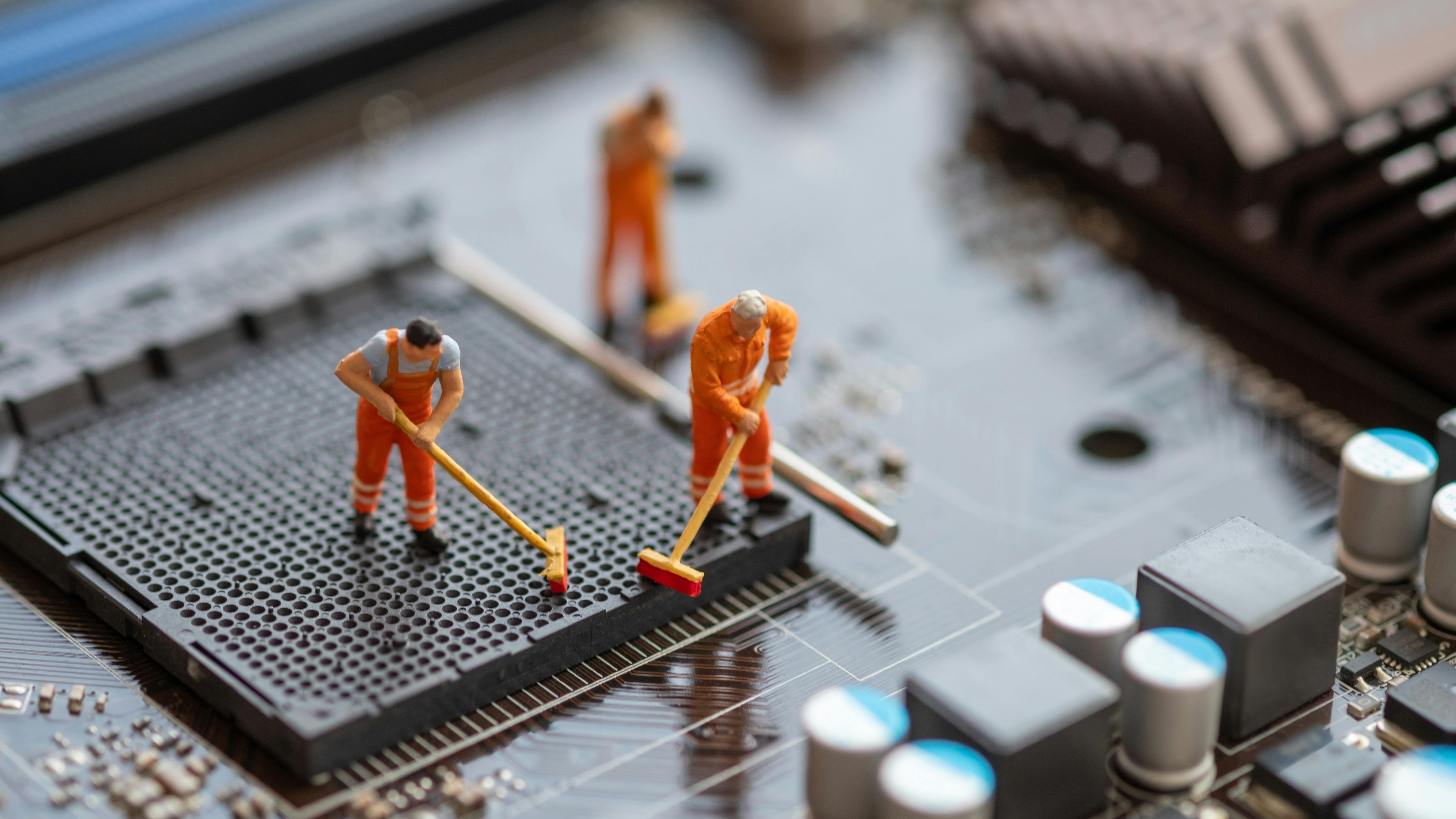 Miniature People: Worker cleaning professional repairman holding a cleaning brush inside old personal computer.